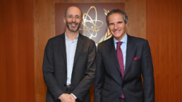 Iran envoy Robert Malley stands with man in front of atomic symbol