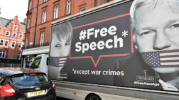 chelsea manning and julian assange image on bus that says free speech, except war crimes