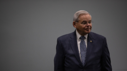 bob menendez stands against a gray background