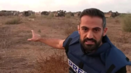 CNN's Jeremy Diamond points toward Israeli military hardware in a field near Israel's border with Gaza