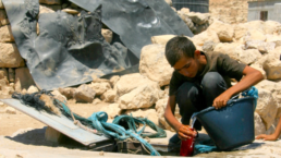 a boy fills a bucket of water in gaza