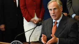 greg abbott sits at a desk