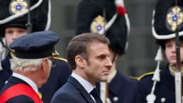 macron stands with soldiers in the background