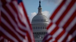 the capitol dome seen between two flags