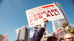 someone holds a sign at a medicare for all rally