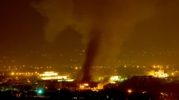 smoke rises from a bombed building at night