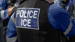 ICE police agent - Officer of Immigration and Customs Enforcement. Close-up of POLICE ICE marking on the back of a stab proof vest uniform worn by a trio of police officers at the scene of an immigrant incident. The ICE federal law enforcement agency is under the supervision of the United States Department of Homeland Security.