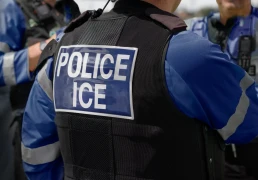 ICE police agent - Officer of Immigration and Customs Enforcement. Close-up of POLICE ICE marking on the back of a stab proof vest uniform worn by a trio of police officers at the scene of an immigrant incident. The ICE federal law enforcement agency is under the supervision of the United States Department of Homeland Security.