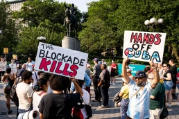 protest signs that say the blockade kills and hands off cuba
