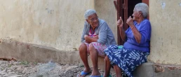 Two old women sitting under the doorway of a home in the colorful town of Trinidad Cuba and talking