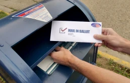 Circa August, 2020 - A man puts an absentee mail-in ballot in the mailbox.