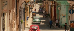 Havana, Cuba 2024 Apr18 - High-angle view of a colorful street in Havana lined with colonial architecture and vintage cars, as local residents walk through Central Havana on a sunny day.
