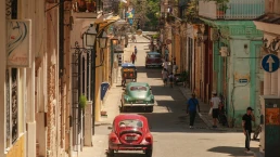 Havana, Cuba 2024 Apr18 - High-angle view of a colorful street in Havana lined with colonial architecture and vintage cars, as local residents walk through Central Havana on a sunny day.