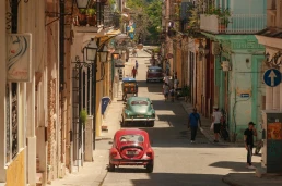 Havana, Cuba 2024 Apr18 - High-angle view of a colorful street in Havana lined with colonial architecture and vintage cars, as local residents walk through Central Havana on a sunny day.