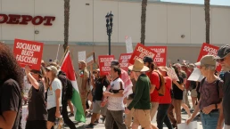 San Diego, California, United States - March 28th, 2026: No Kings peaceful protest march at waterfront park, people holding anti ice, trump, fascism, war signs on sunny day, socialism beats fascism democratic socialists of america signs (dsa) with downtown san diego high rise buildings backdrop