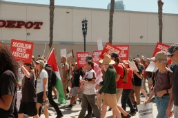 San Diego, California, United States - March 28th, 2026: No Kings peaceful protest march at waterfront park, people holding anti ice, trump, fascism, war signs on sunny day, socialism beats fascism democratic socialists of america signs (dsa) with downtown san diego high rise buildings backdrop